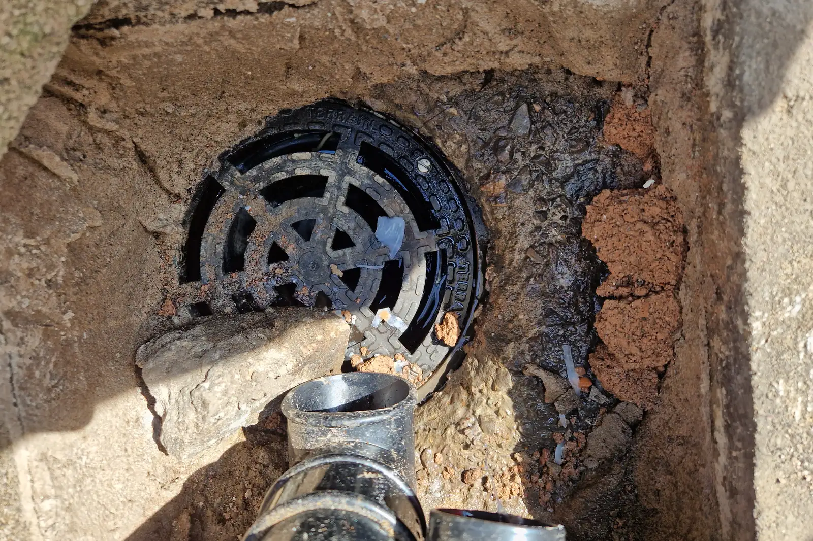 Rats in Drains: How They Get In and Who Fixes What 1 A broken rainwater gully surround with a rock over a hole in the grate